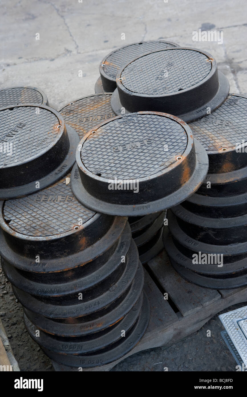 Stack of circular cast iron manhole covers with SEWER molded into top Stock Photo