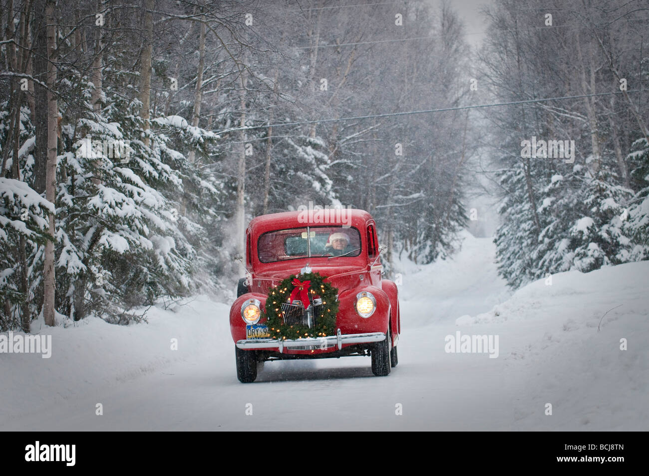 Man driving a vintage 1941 Ford pickup with a Christmas wreath on the