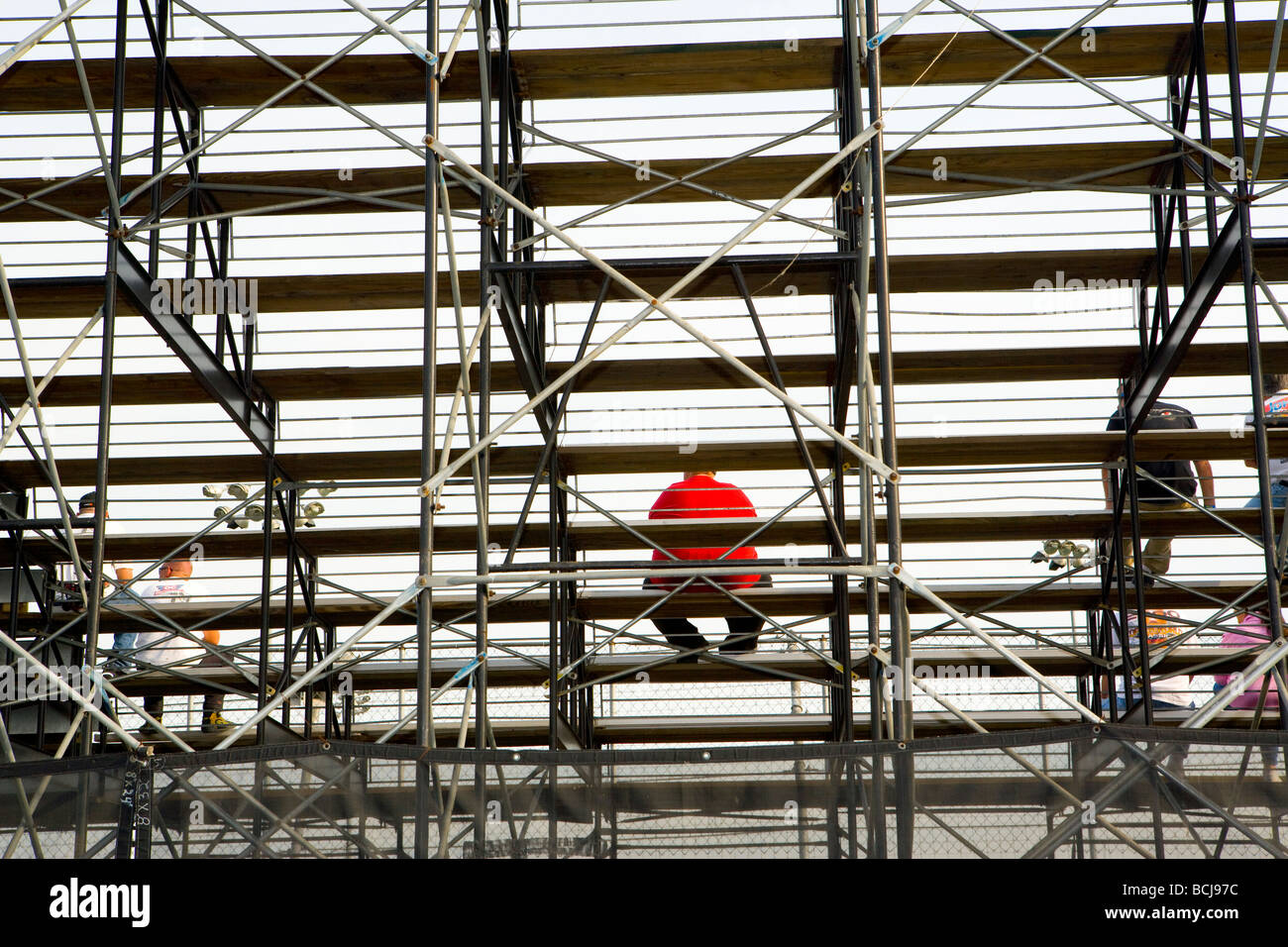 Person in red shirt sitting in stadium bleachers seating stands Stock Photo