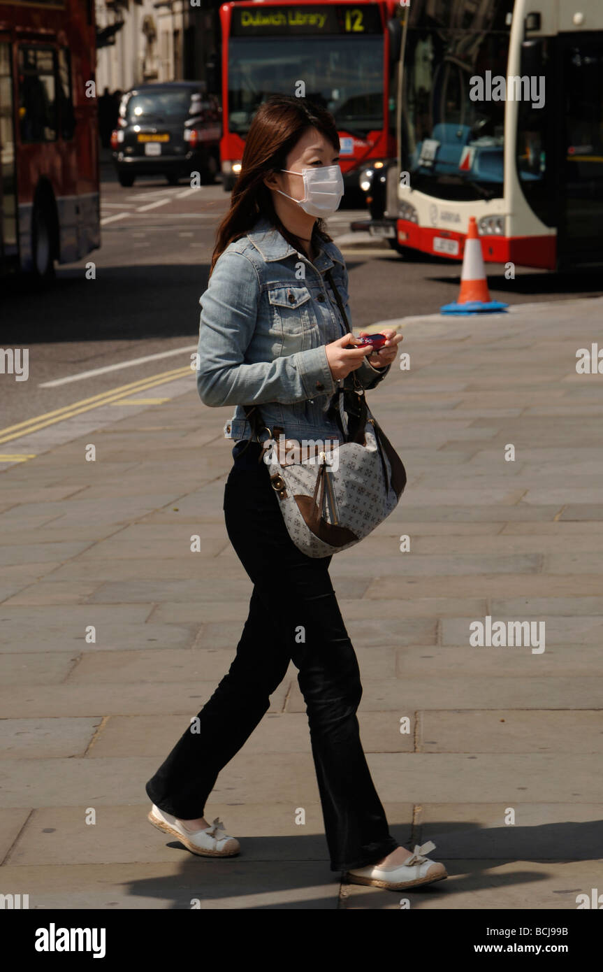 asian girl tourist wearing a protective face mask to prevent Covid Coronavirus in trafalgar square London Stock Photo