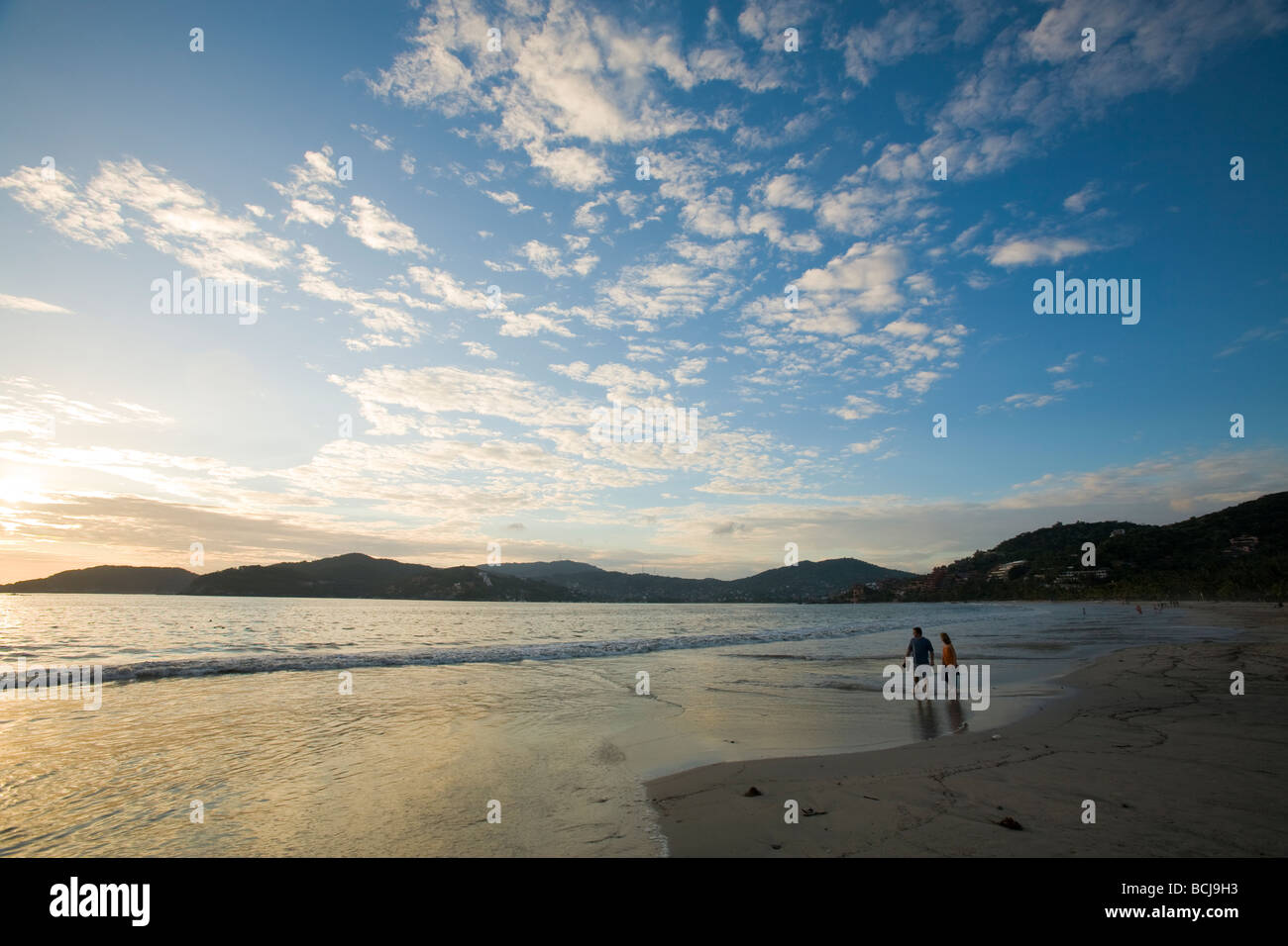 Zihuatanejo Mexico Male and female couple walking on beach of Playa La Madera in Zihuatanejo Mexico during dramatic sunset Stock Photo