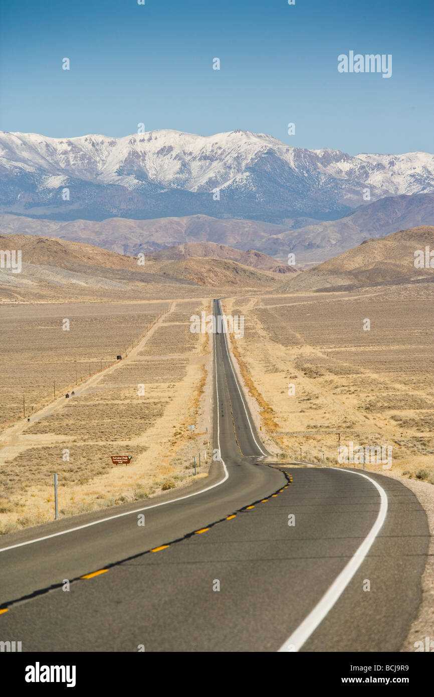 Nevada Highway 50, straight road in desert, road is known as 'Loneliest Highway in America'  Snow-capped mountains in distance. Stock Photo