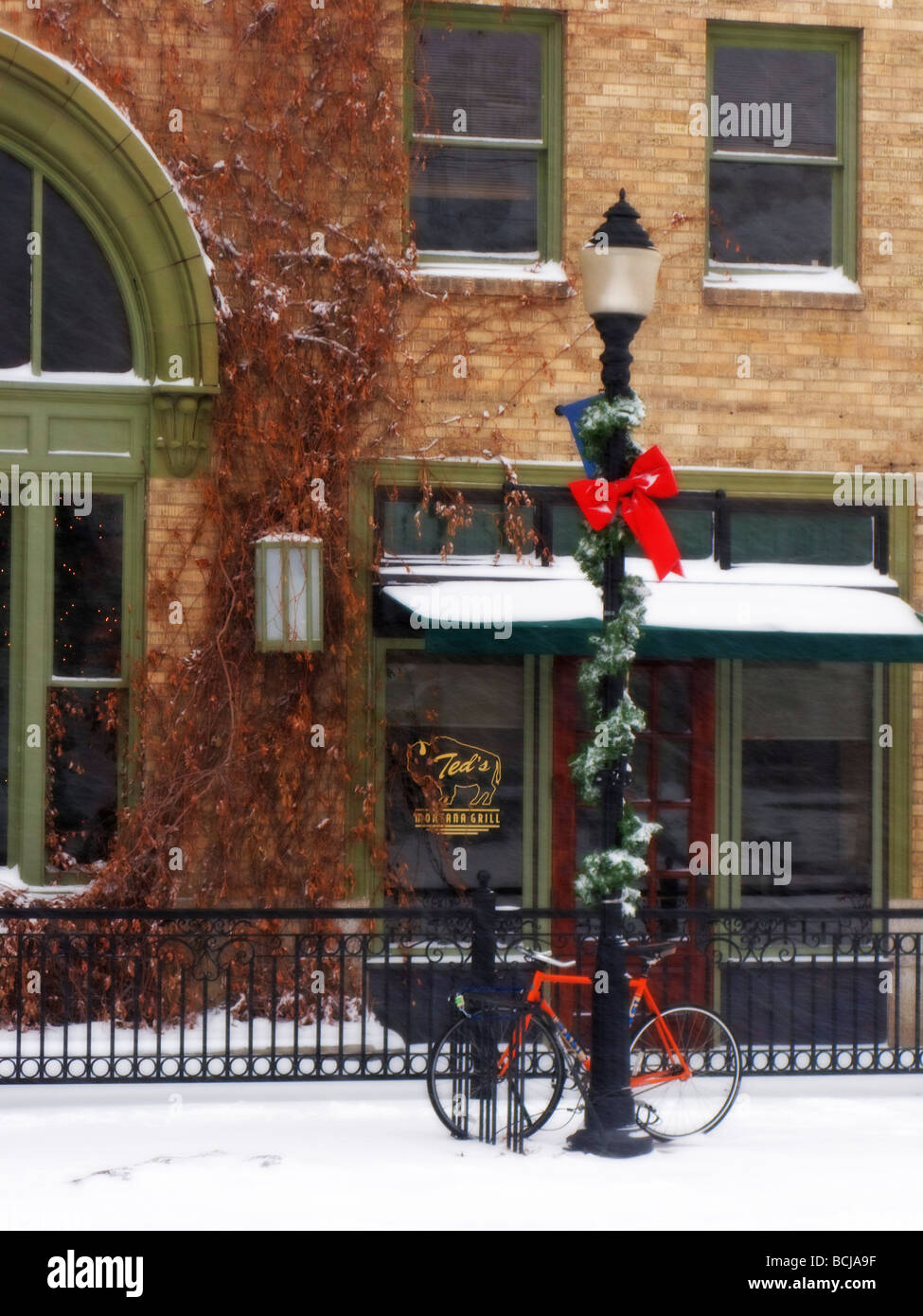 Bicycle leaning against a lamp post decorated for Christmas during Winter in Bozeman, Montana Stock Photo