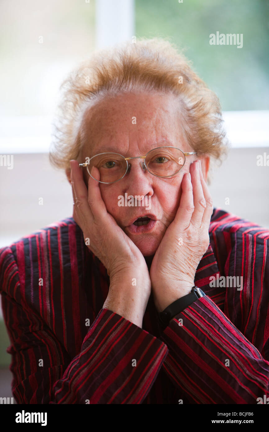 An old woman sits thoughtfully at the window Stock Photo