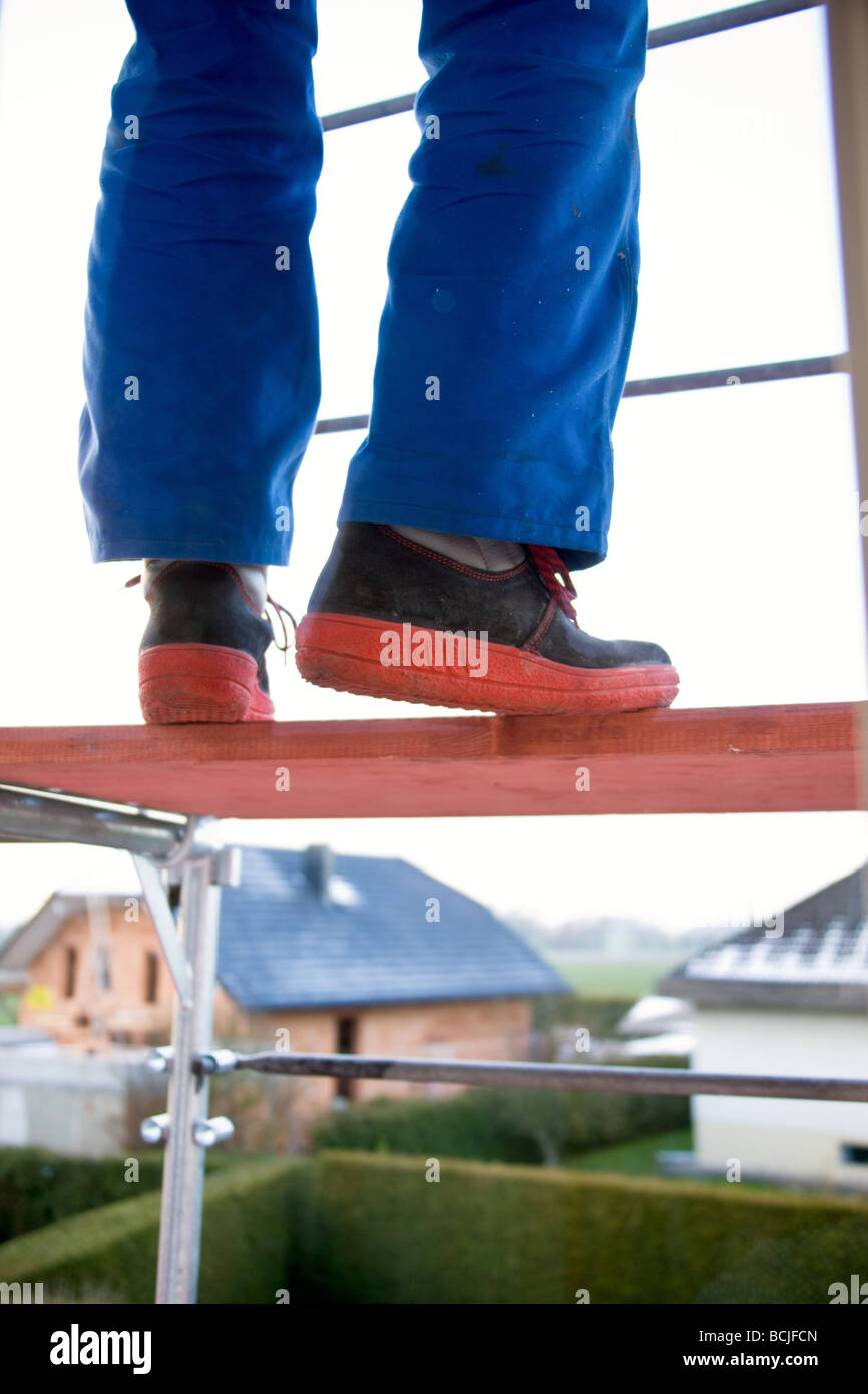 Craftsmen in the bluey balancing on a scaffolding Stock Photo