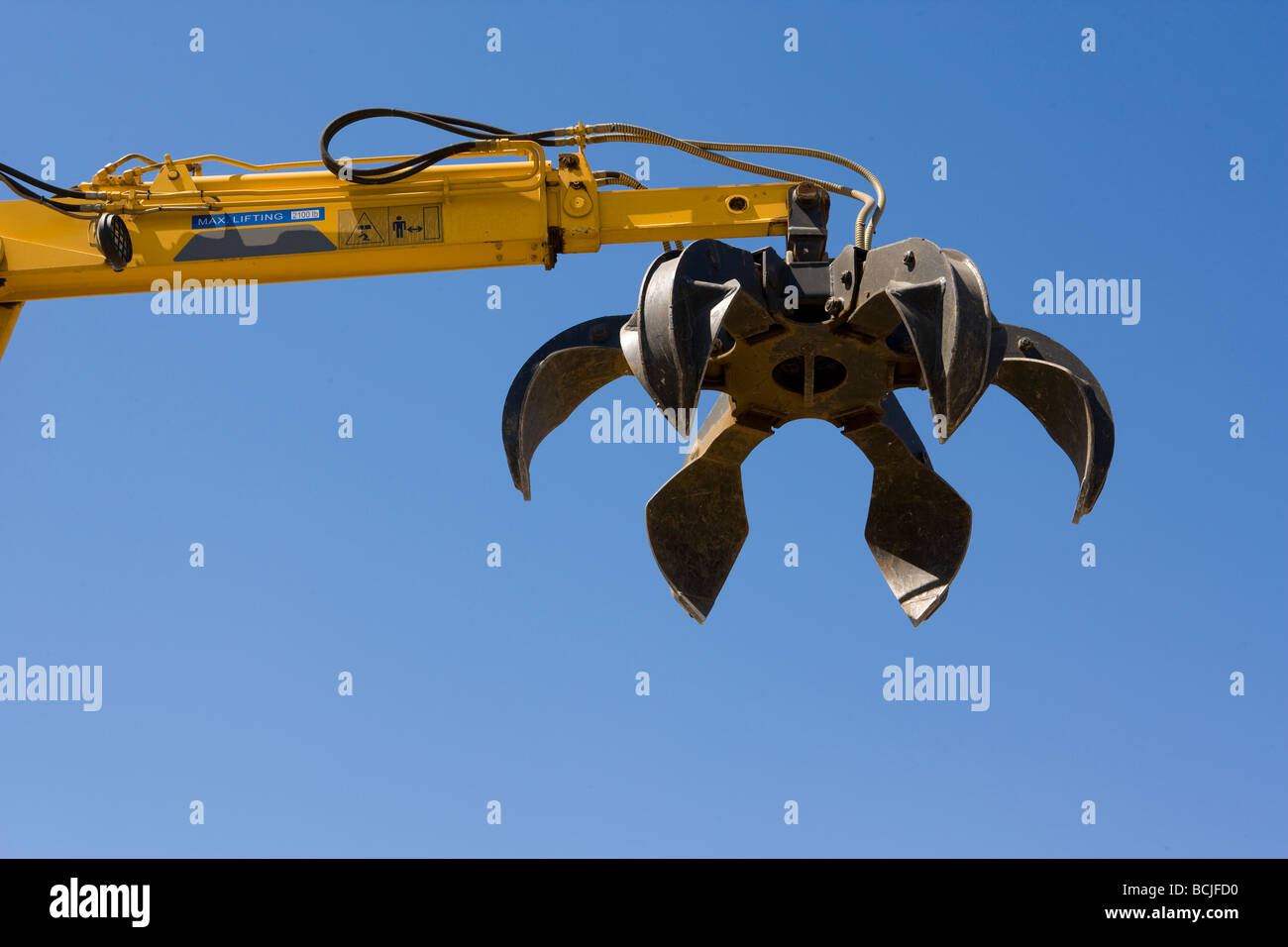 Claw of yellow mechanical machine used for picking up scrap metal at recylcing yard against blue sky Indio California USA Stock Photo