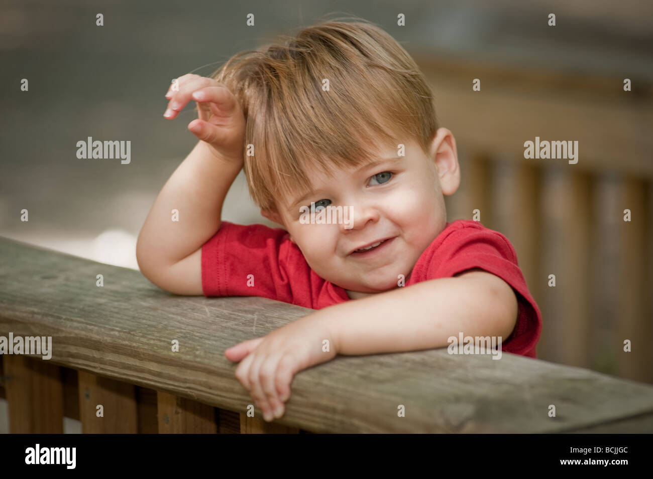 Little boy in red shirt with hands over deck railing Stock Photo