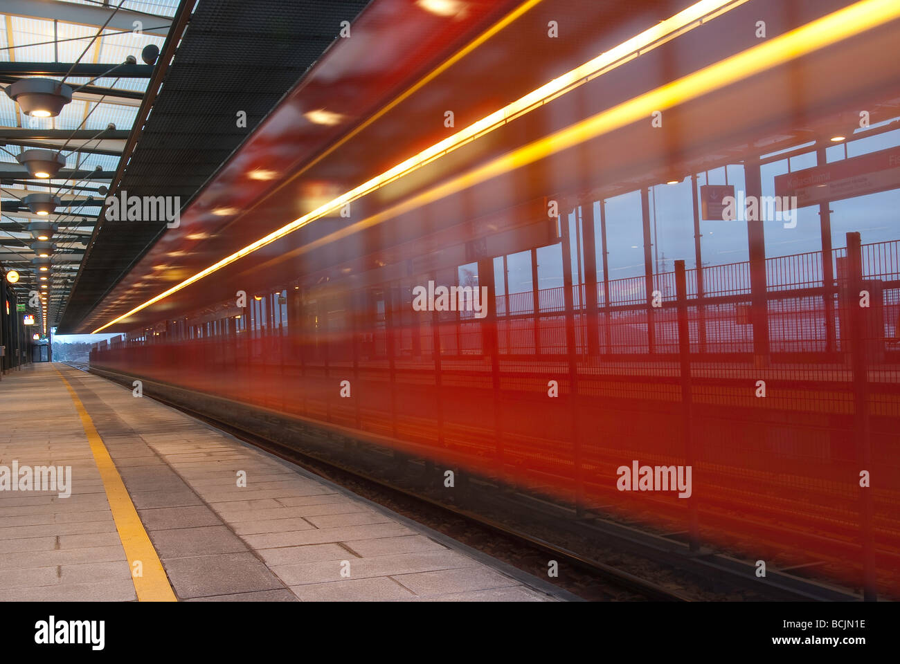 Red subway train speeding through a subway station Stock Photo