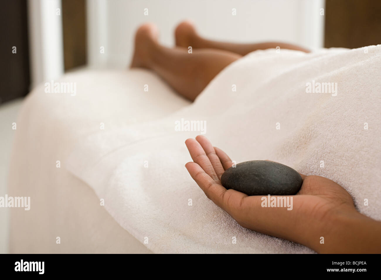 Woman on massage table holding stone Stock Photo