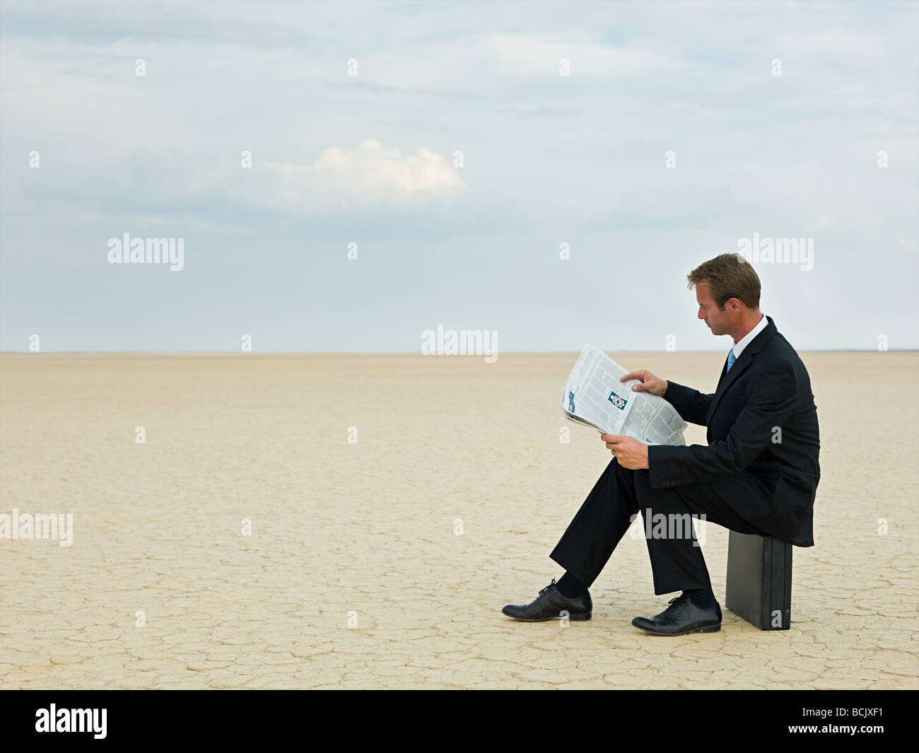 Businessman reading a newspaper in the desert Stock Photo