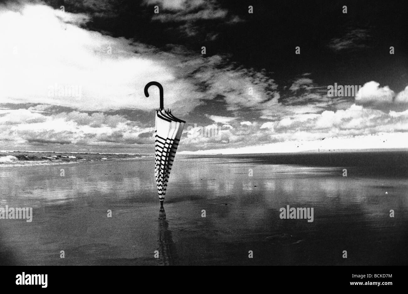 Umbrella stuck into sand on beach, b&w Stock Photo Alamy