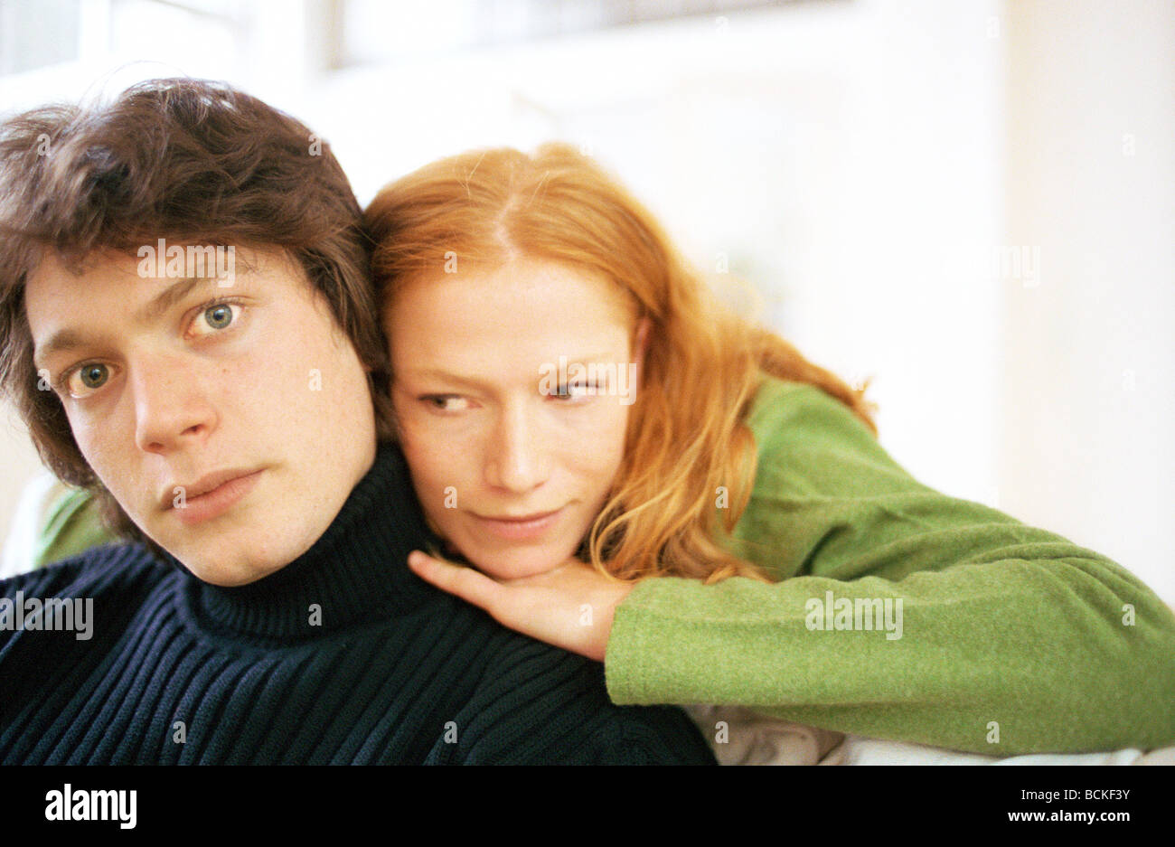 Young woman leaning on young man's shoulder from behind Stock Photo