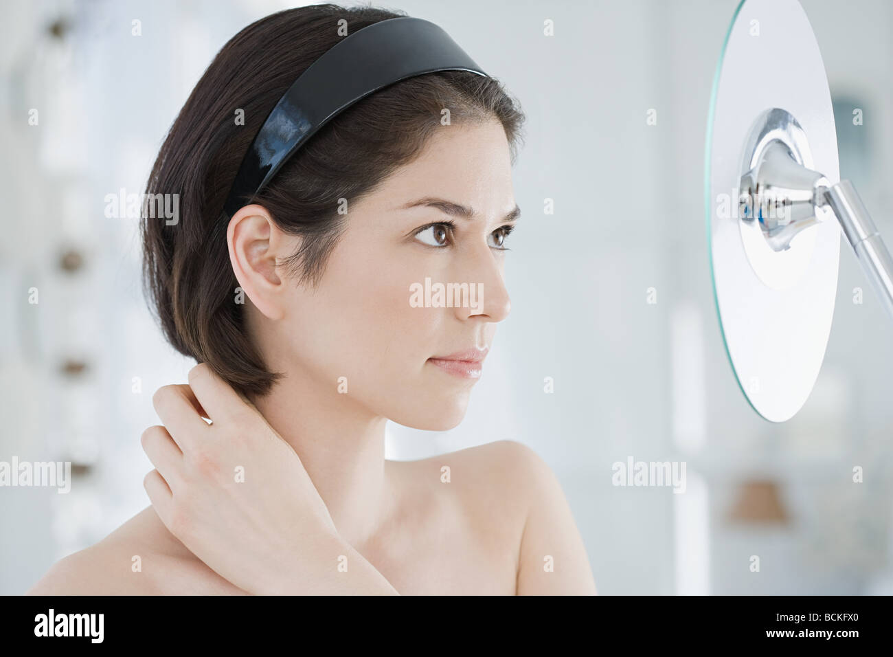 Young woman looking in mirror Stock Photo - Alamy