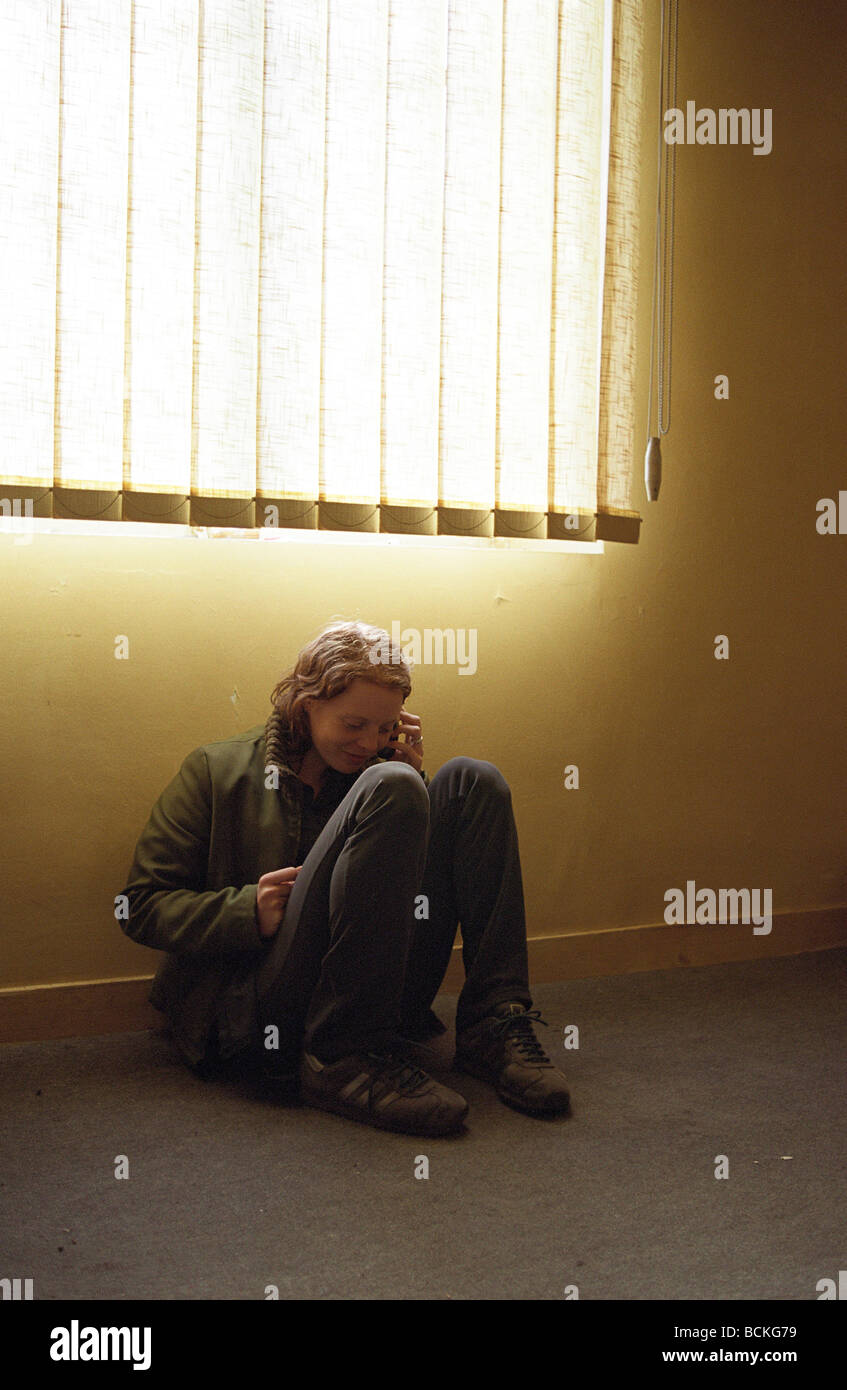 Young woman sitting on floor, using mobile phone Stock Photo - Alamy