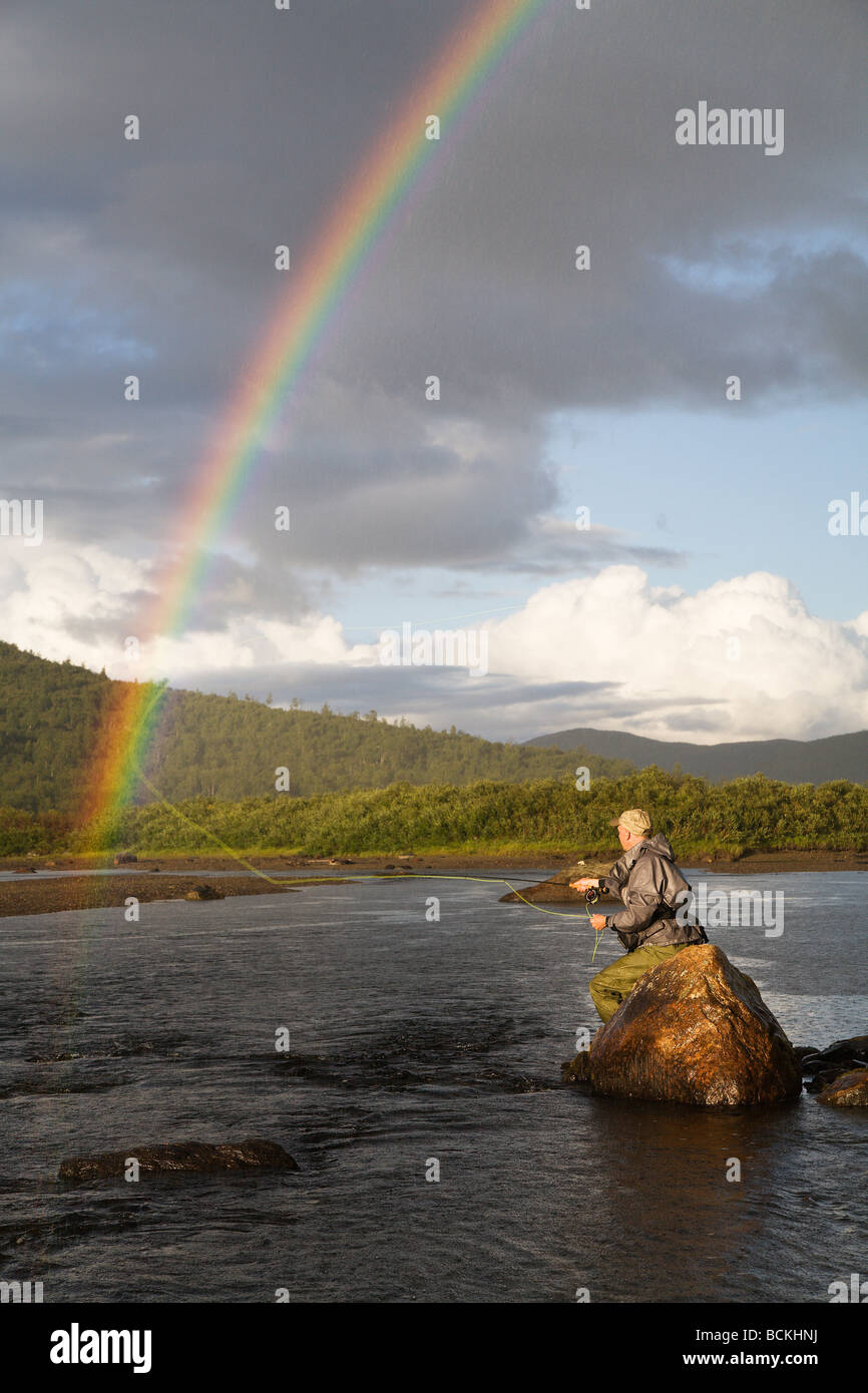 Flyfisherman and rainbow over a troutstream Stock Photo