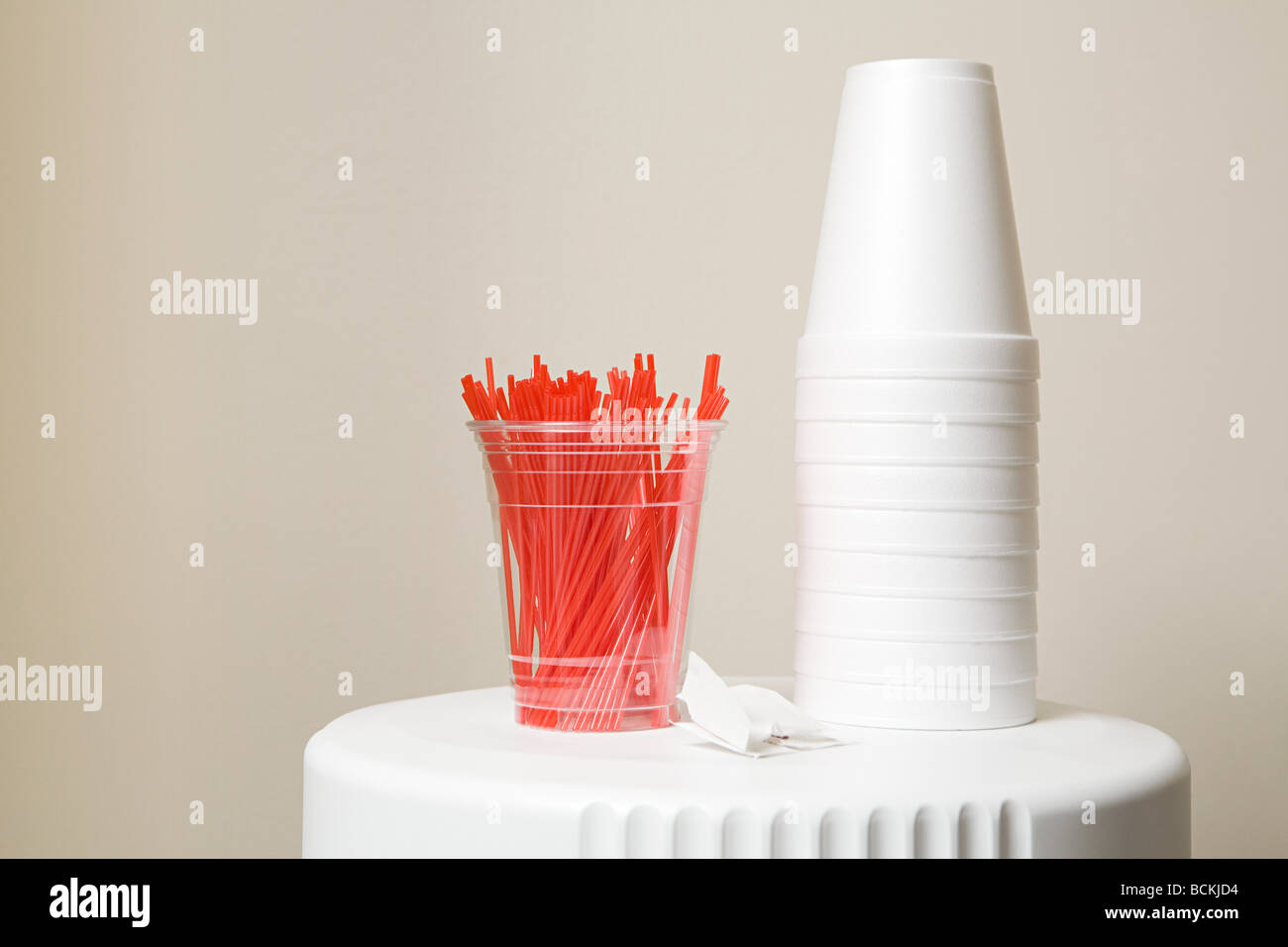 Polystyrene cups and plastic stirrers on top of coffee machine Stock Photo