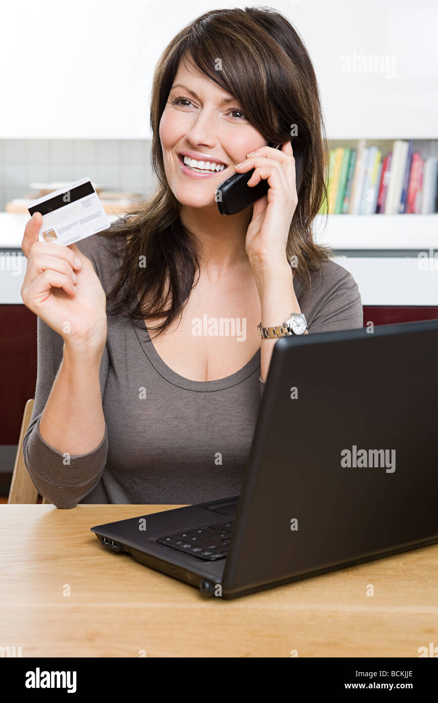 Woman with cellphone credit card and laptop Stock Photo