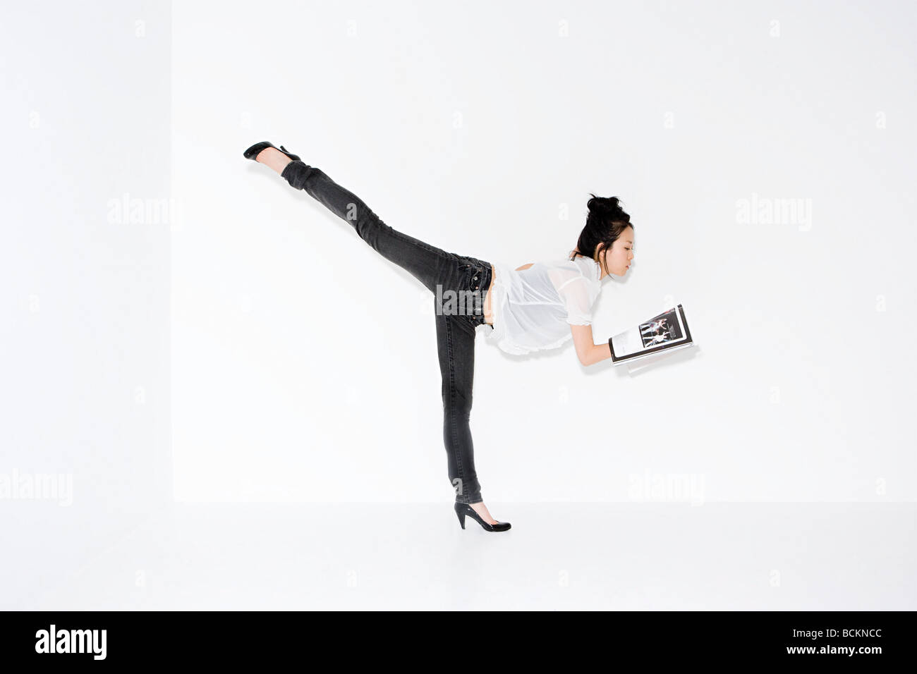 Woman on one leg with magazine Stock Photo