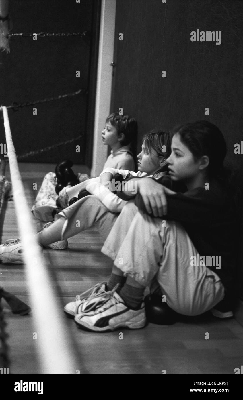 Girls sitting against wall, side view, b&w Stock Photo