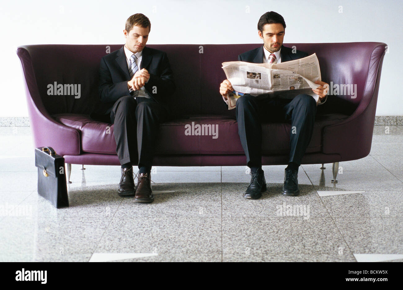 Two businessmen sitting on sofa Stock Photo - Alamy