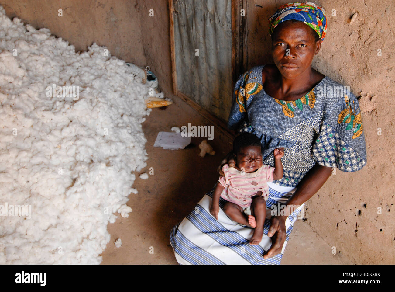 West Africa Burkina Faso , fairtrade and organic cotton project , wife of cotton farmer with child at cotton store in their hut Stock Photo
