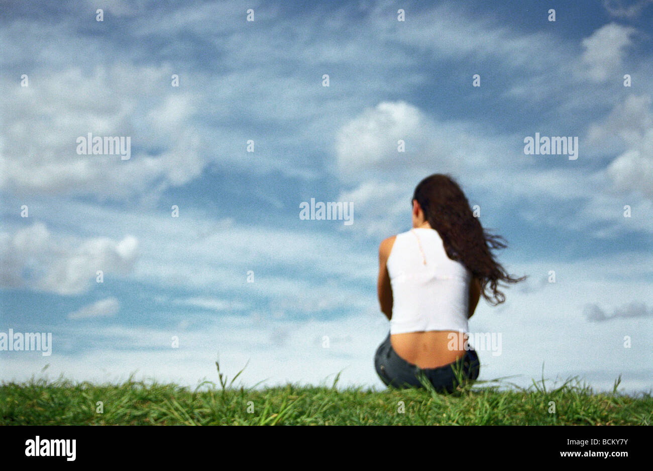 Woman sitting on grass, rear view Stock Photo