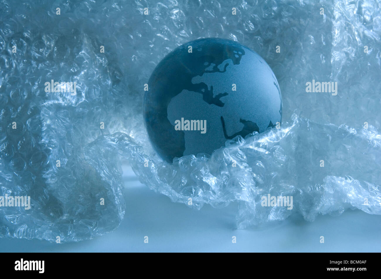 Glass 'earth' sphere surrounded by plastic bubble wrap. Stock Photo