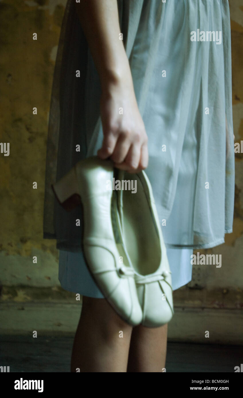 Woman in dress, holding pair of shoes by side, cropped, side view Stock Photo