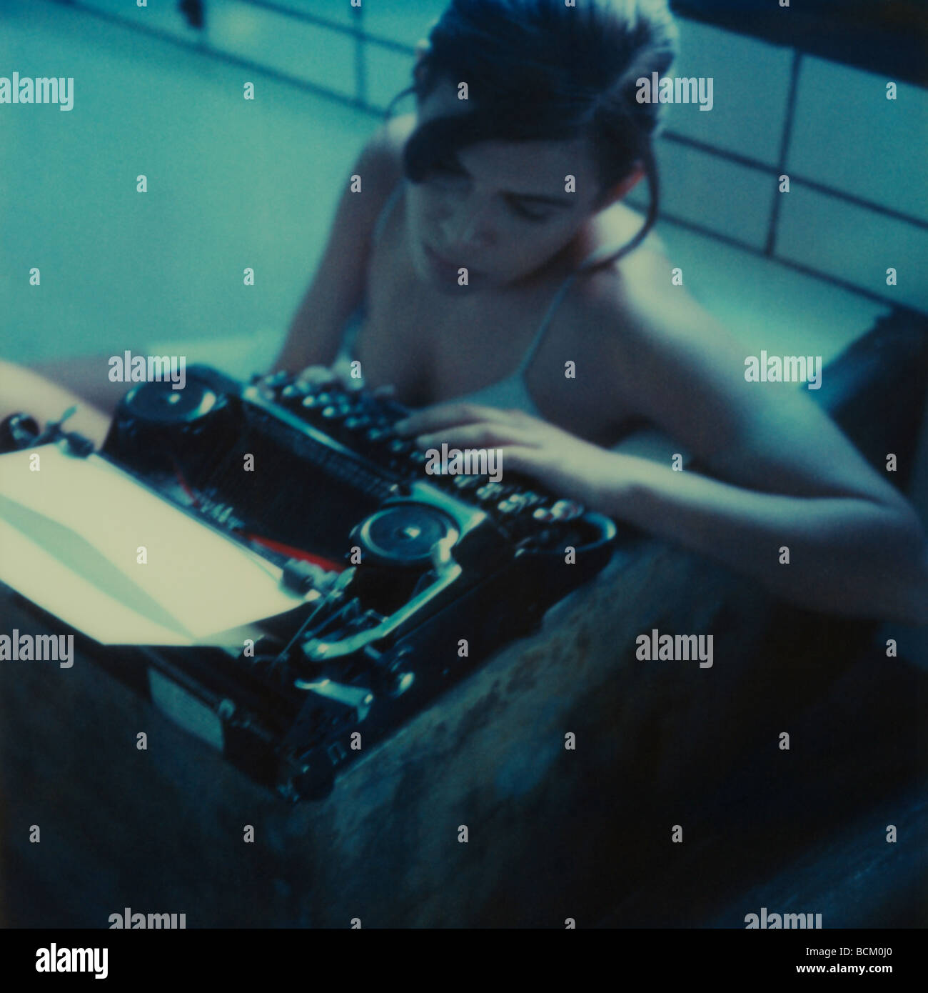 Woman sitting in bathtub, using typewriter Stock Photo