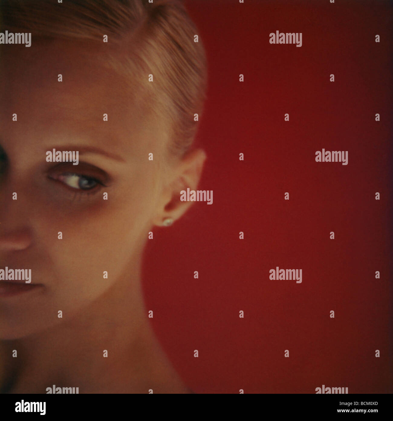 Woman looking away, cropped view of face against red background, close-up Stock Photo