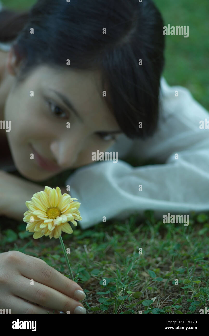 Woman lying on grass, picking flower, close-up Stock Photo