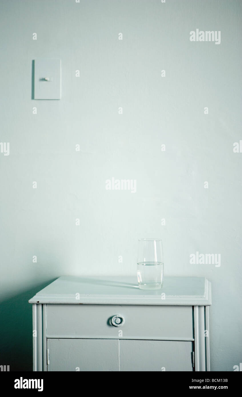 Glass of water on top of nightstand, in front of wall Stock Photo Alamy