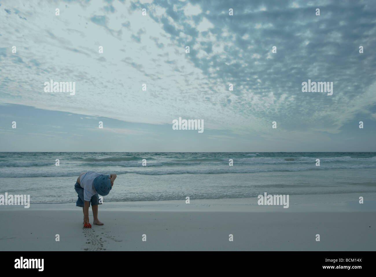 Boy bending over on beach, making lines in sand Stock Photo Alamy