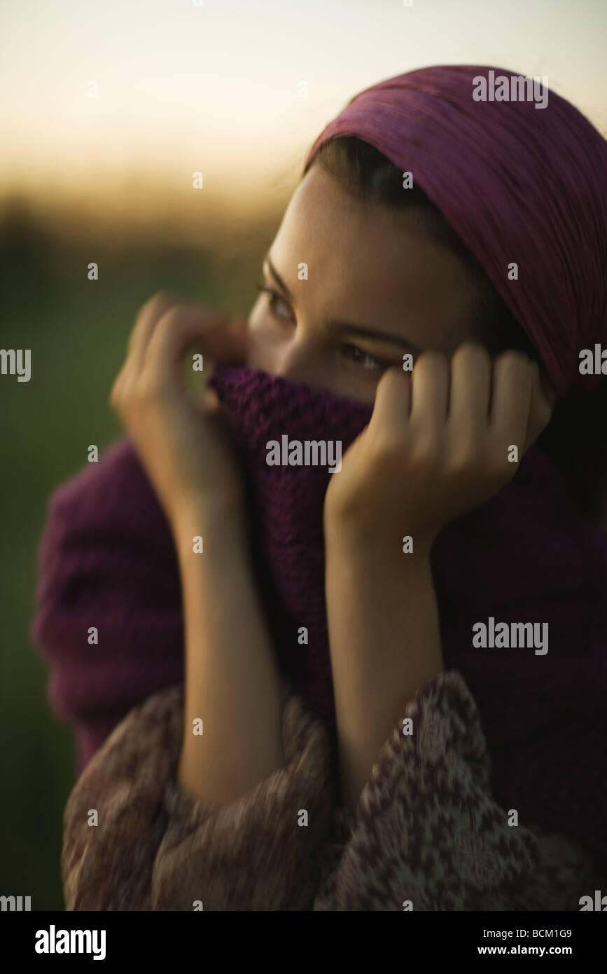 Woman pulling sweater up over mouth, looking away, closeup Stock Photo