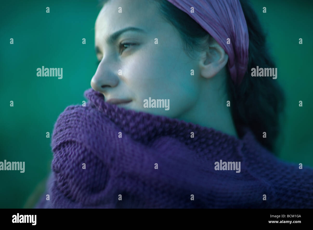 Woman pulling sweater up to face, looking away, close-up Stock Photo