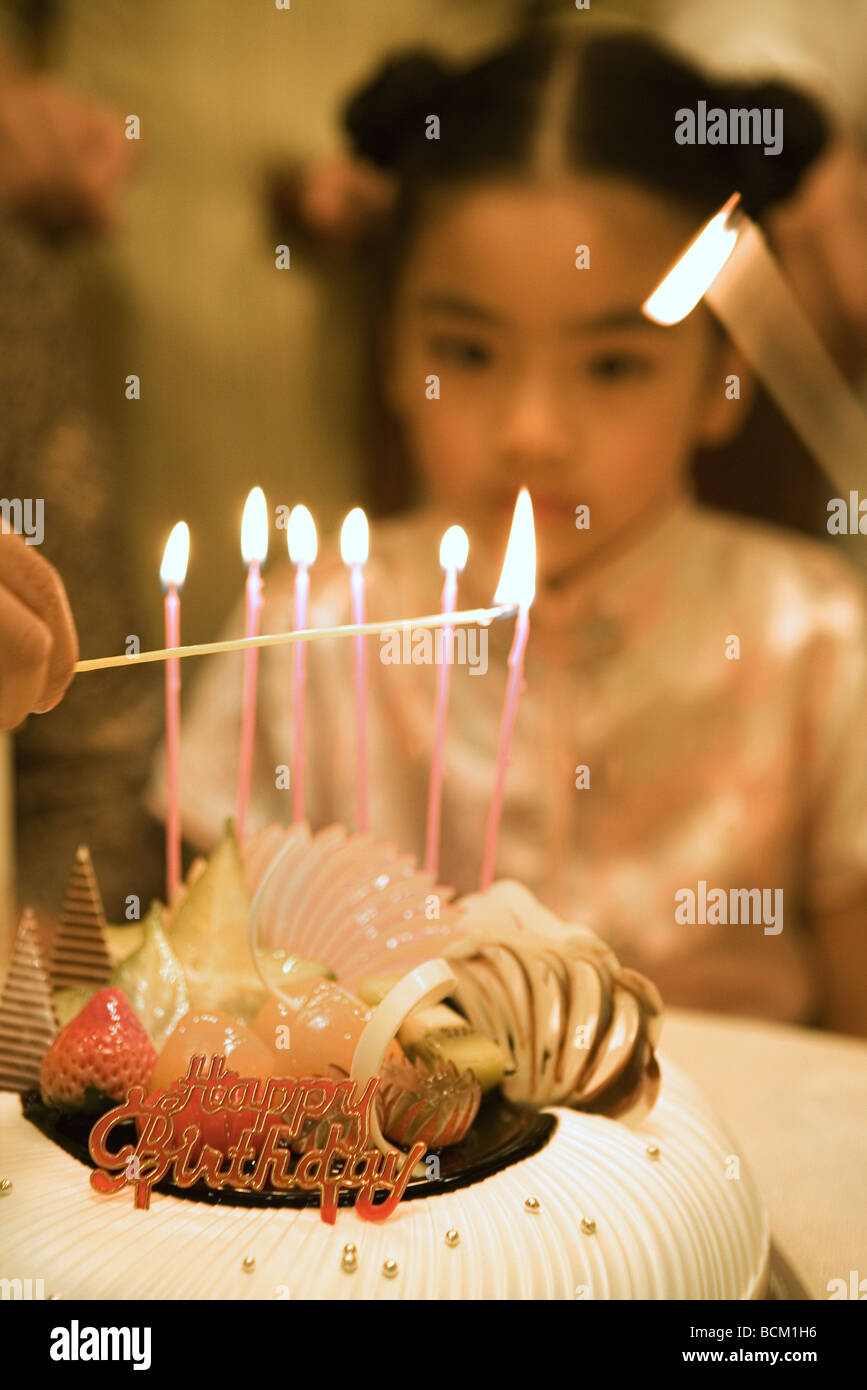 Birthday candles being lit while little girl watches, cropped Stock Photo Alamy