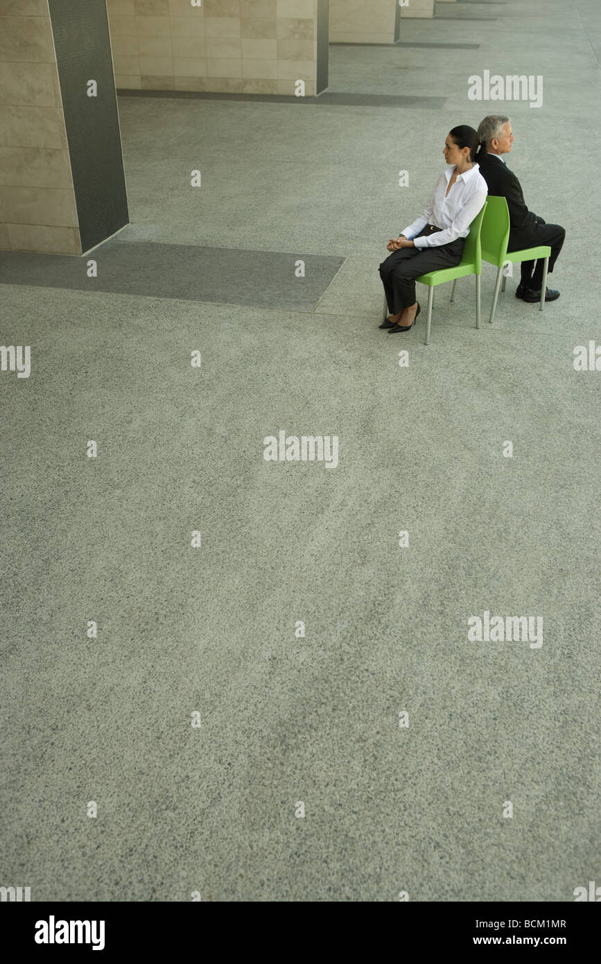 Businesswoman and businessman sitting back to back, high angle view, full length Stock Photo
