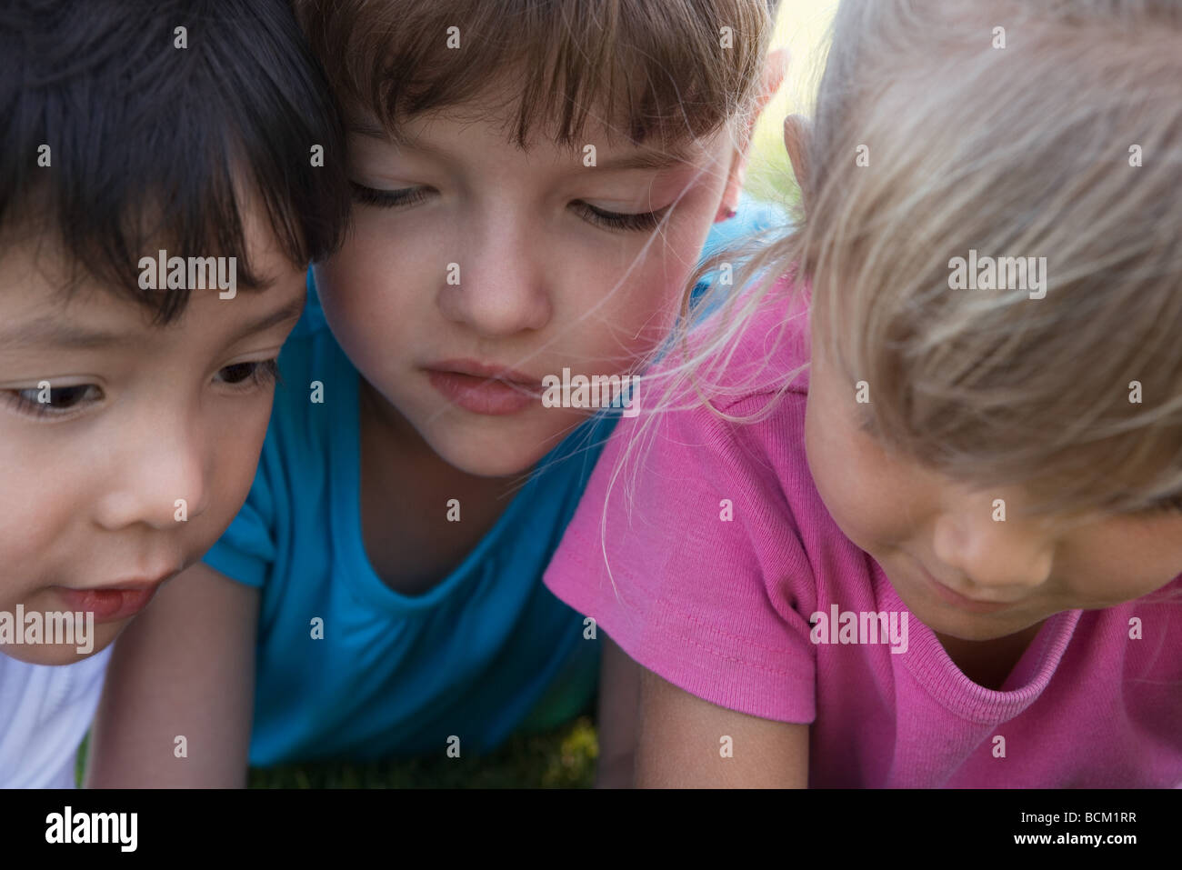 Three children with heads close together, cropped Stock Photo Alamy