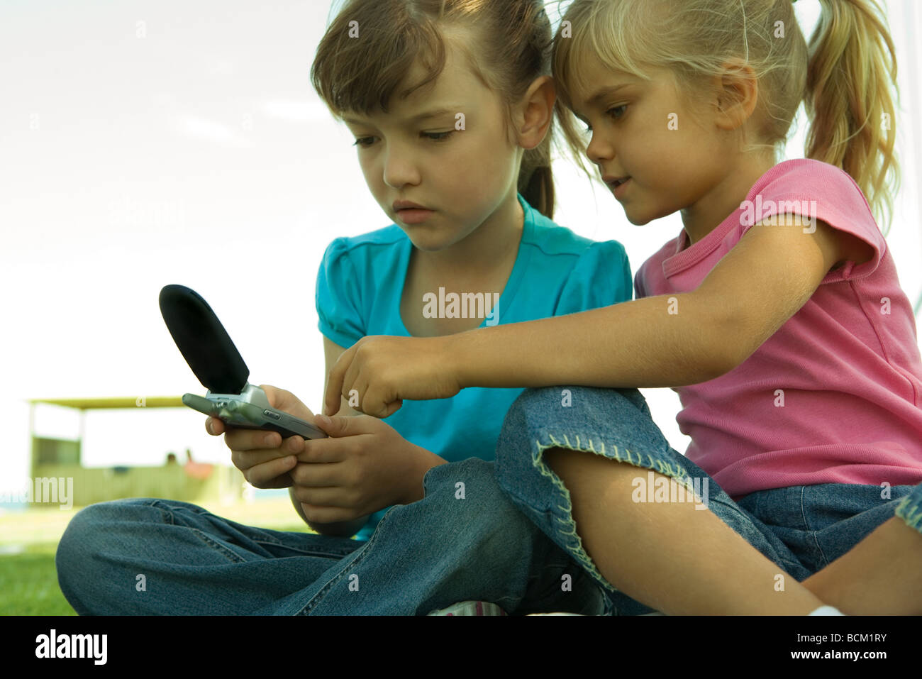 Girls using cell phone together, low angle view Stock Photo