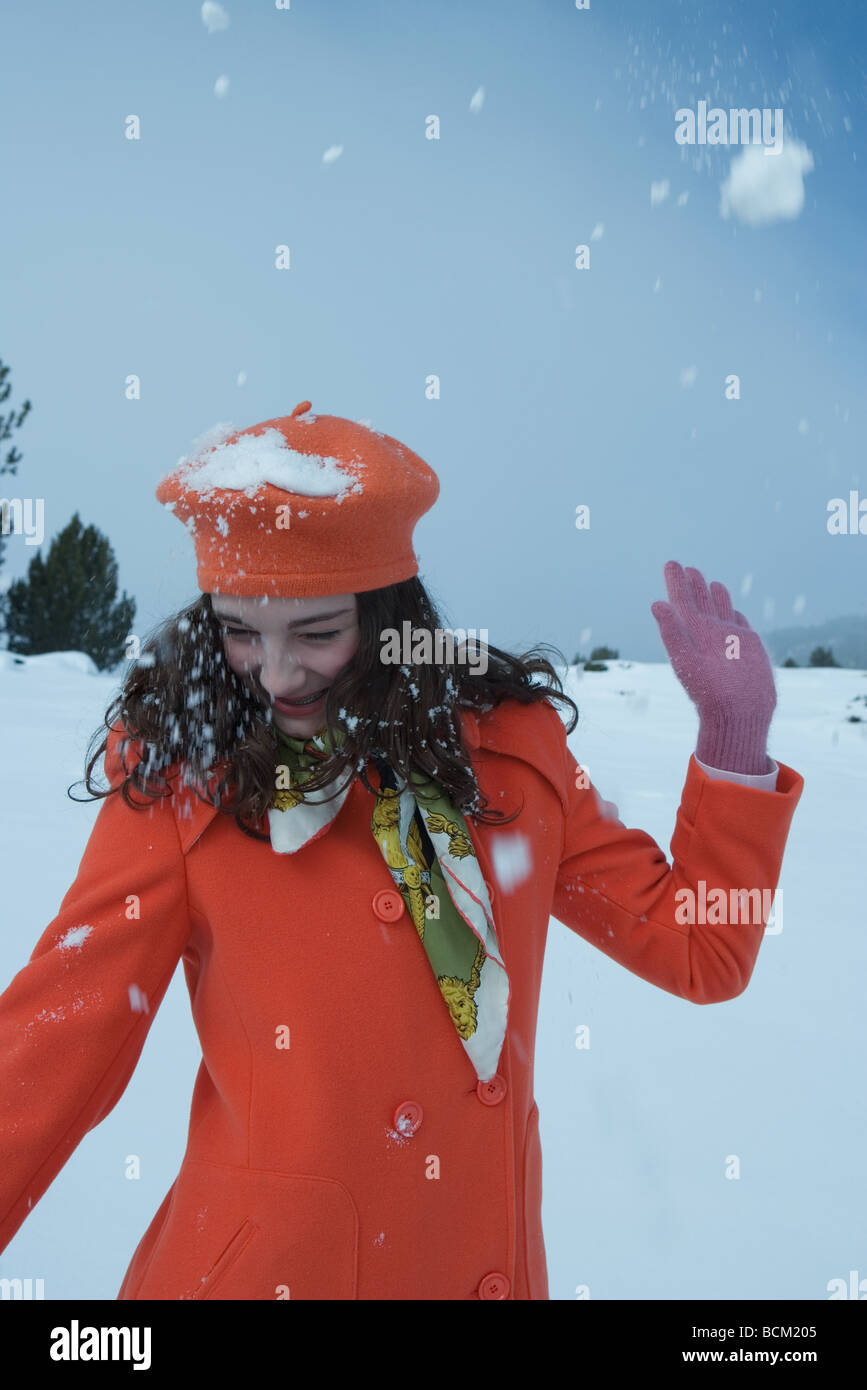 Teenage girl being hit with snowball, looking away, smiling Stock Photo