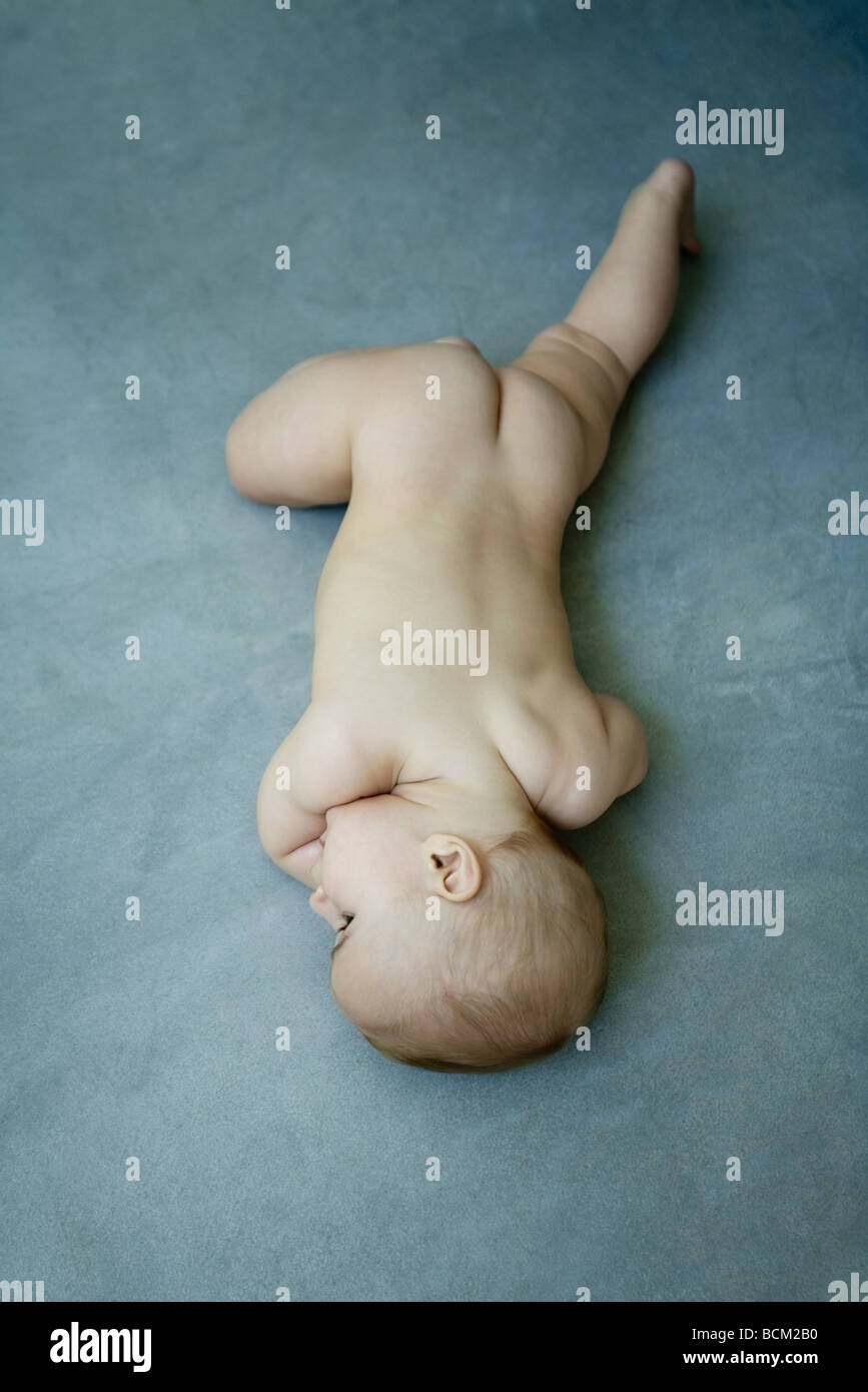 Nude baby lying on stomach on the ground, full length, high angle view  Stock Photo - Alamy