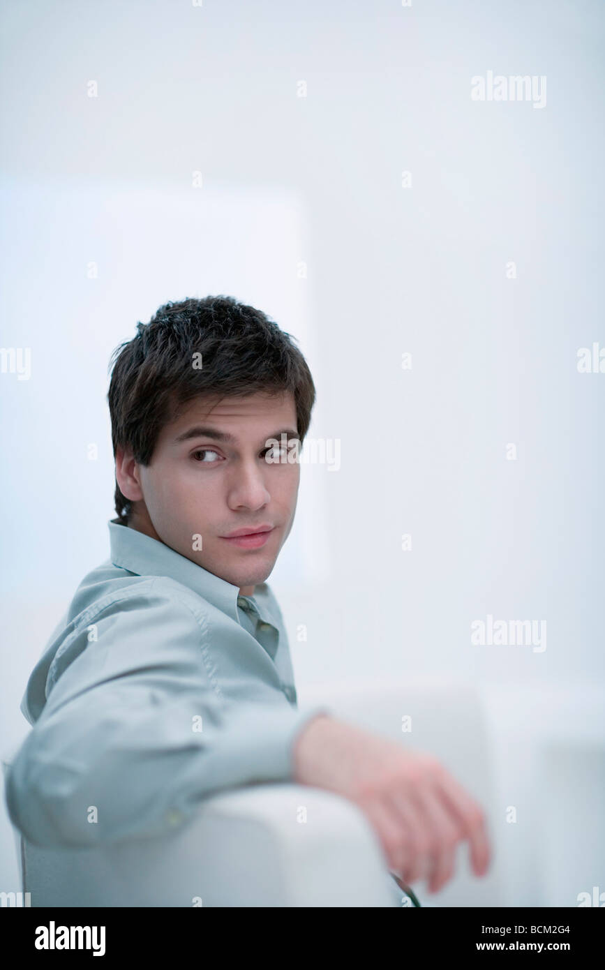 Man sitting on sofa, looking over shoulder Stock Photo