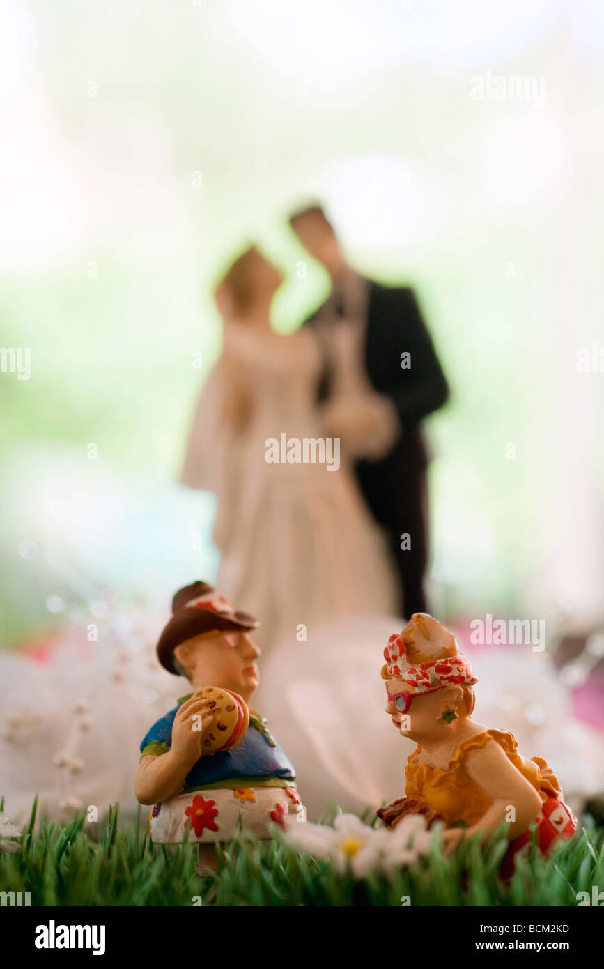 Miniature couple having picnic on fake grass, bride and groom figurine in background Stock Photo