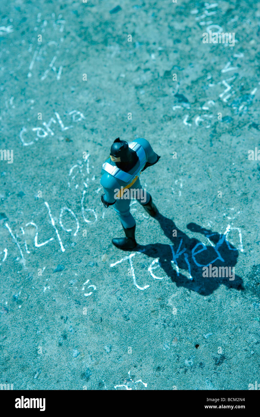 Toy figure standing on graffitied surface, high angle view Stock Photo