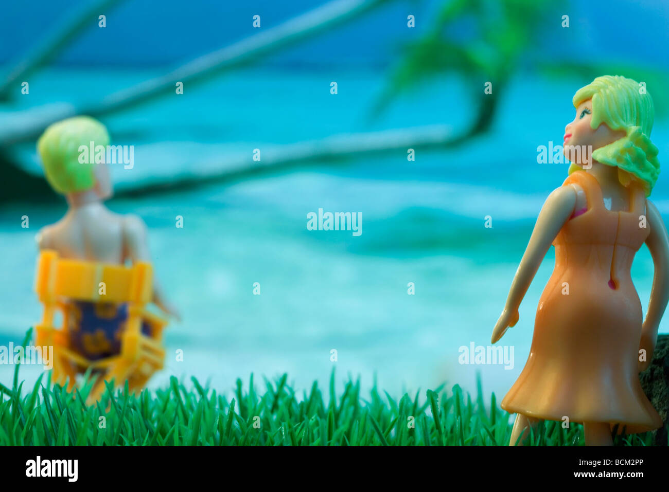 Plastic woman approaching plastic man sitting in chair at beach Stock