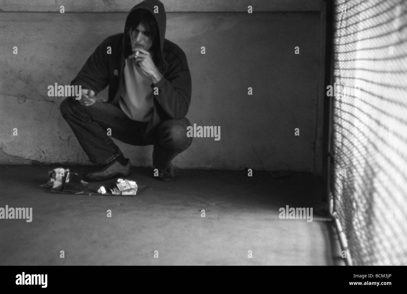 Thief smoking cigarette, looking at contents of stolen wallet Stock Photo