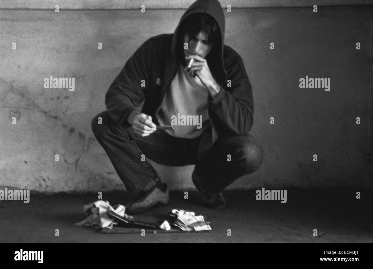 Thief smoking cigarette, looking at contents of stolen wallet Stock Photo