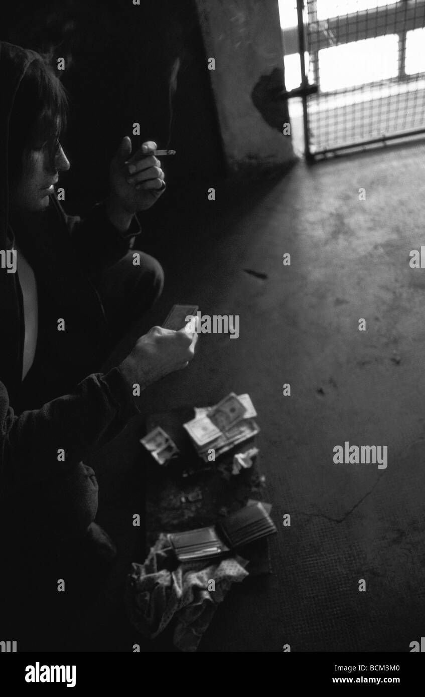 Thief smoking cigarette, looking at contents of stolen wallet Stock Photo
