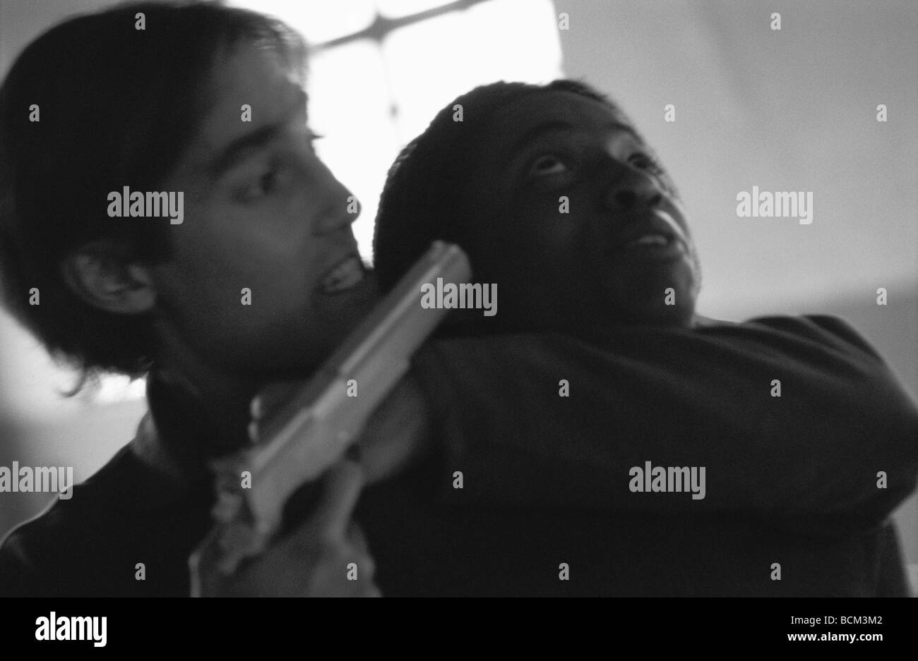 Thief holding gun to person's head Stock Photo