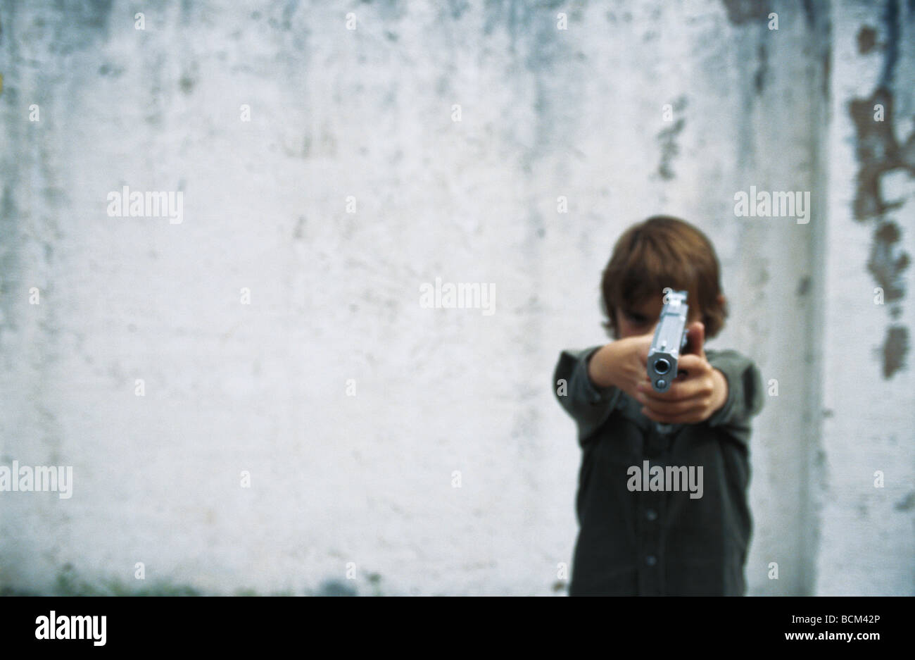 Boy aiming gun at camera Stock Photo